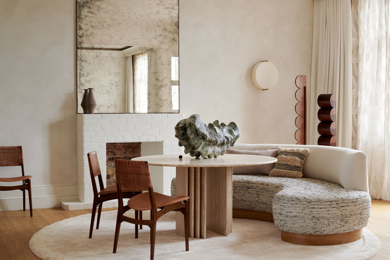 A well lit living room with table, chair, mirror and sofa