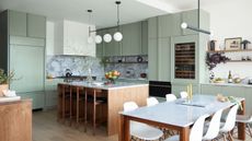 A wood and sage green kitchen with statement lighting