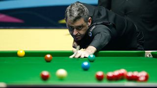 Snooker player Ronnie O'Sullivan takes a shot, with red, yellow, green, brown and blue balls visible