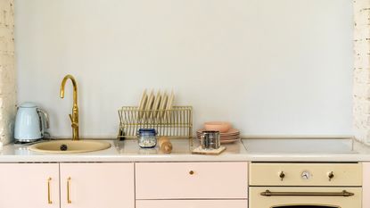 A kitchen with pink kitchen appliances, pink cabinets and pink plates