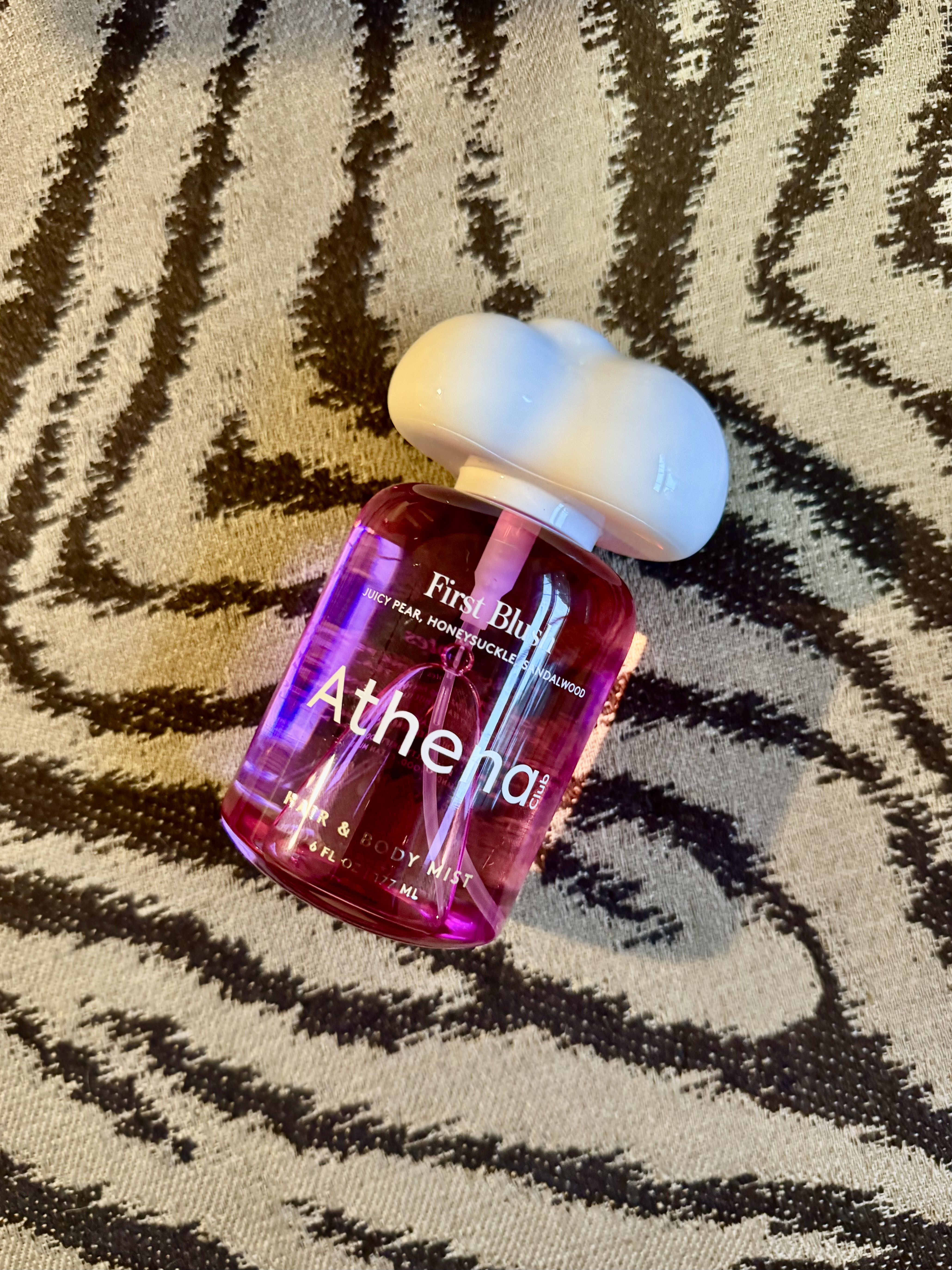 a pink perfume bottle of First Blush body mist by Athena Club on a tiger striped carpet