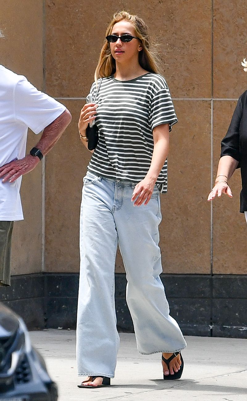 Tate McRae wearing a striped T-shirt, light-wash jeans, and wedge-heel flip-flops