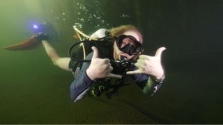 Man swimming in scuba gear in murky water