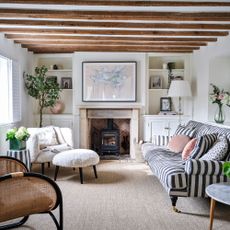 Living room with log burner and a striped sofa on the right, and a fluffy accent chair on the right