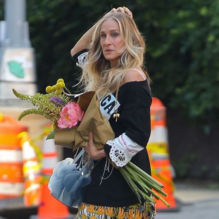 Sarah Jessica Parker holds a bouquet of flower in New York wearing a colourful midi skirt with orange slingback heels.