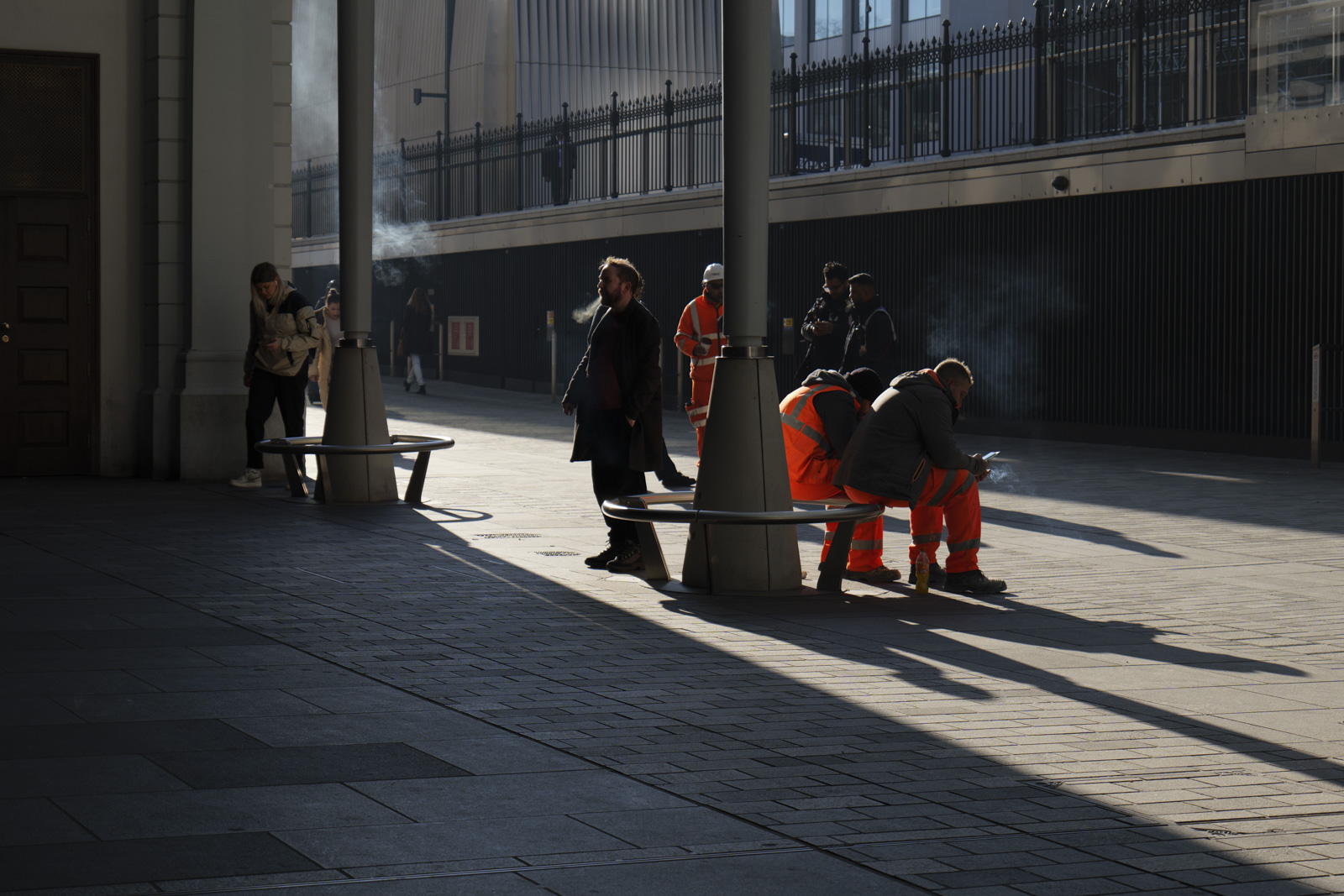 Picture taken with Panasonic S5 II of London street with smokers in shaft of light