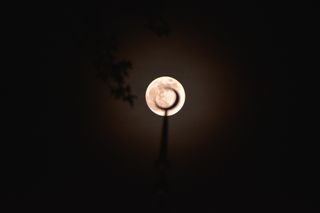 The bright full moon silhouetting a crescent moon structure on a building