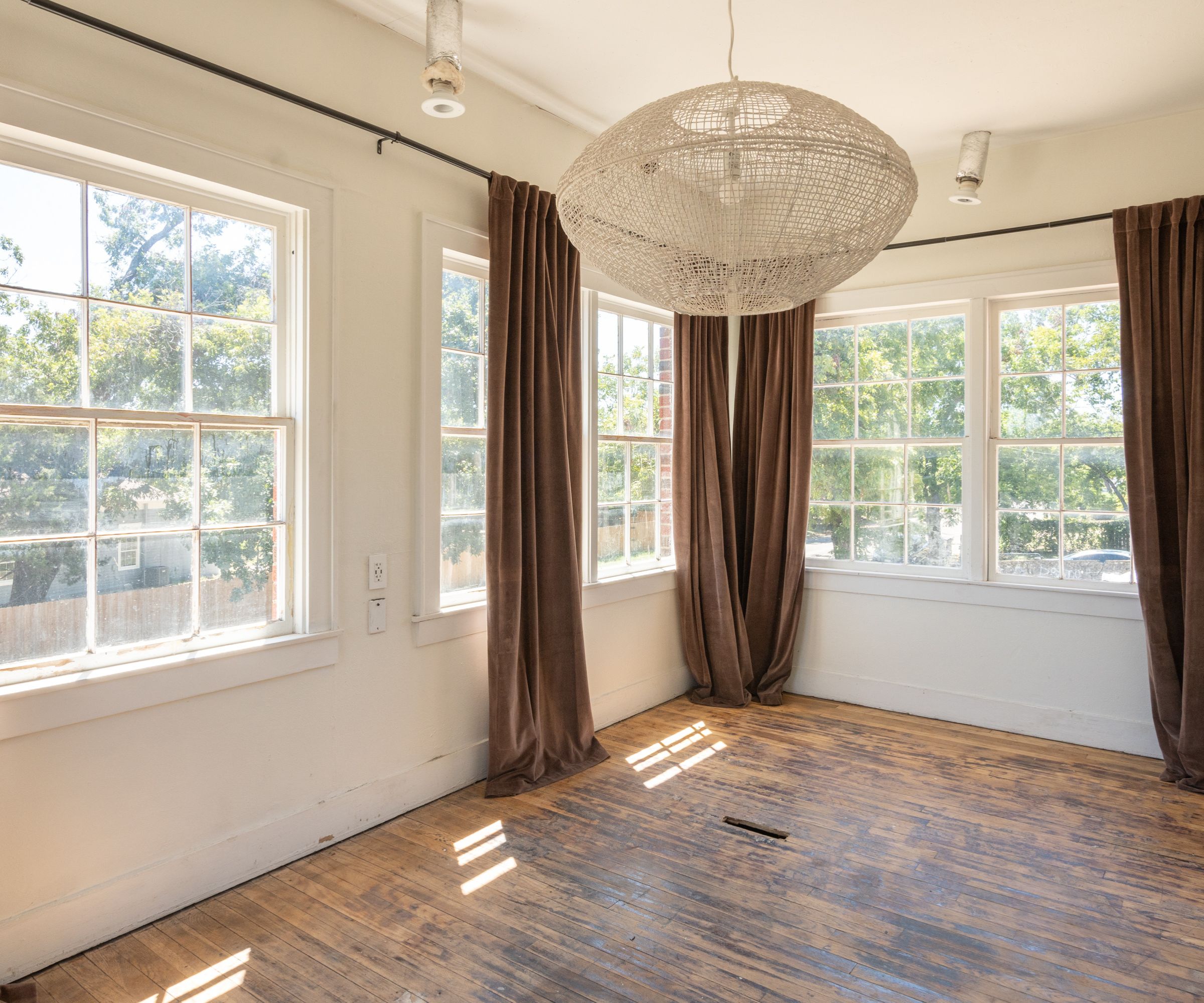 Sunroom with large windows, wood floor, white walls and rattan light