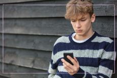 Worried teenage boy looking at his phone