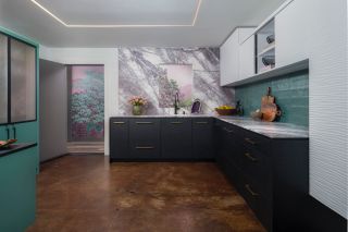 A kitchen with marble worktop and backsplash with wallpaper visible from the hallway