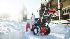 Snow blower with home in background