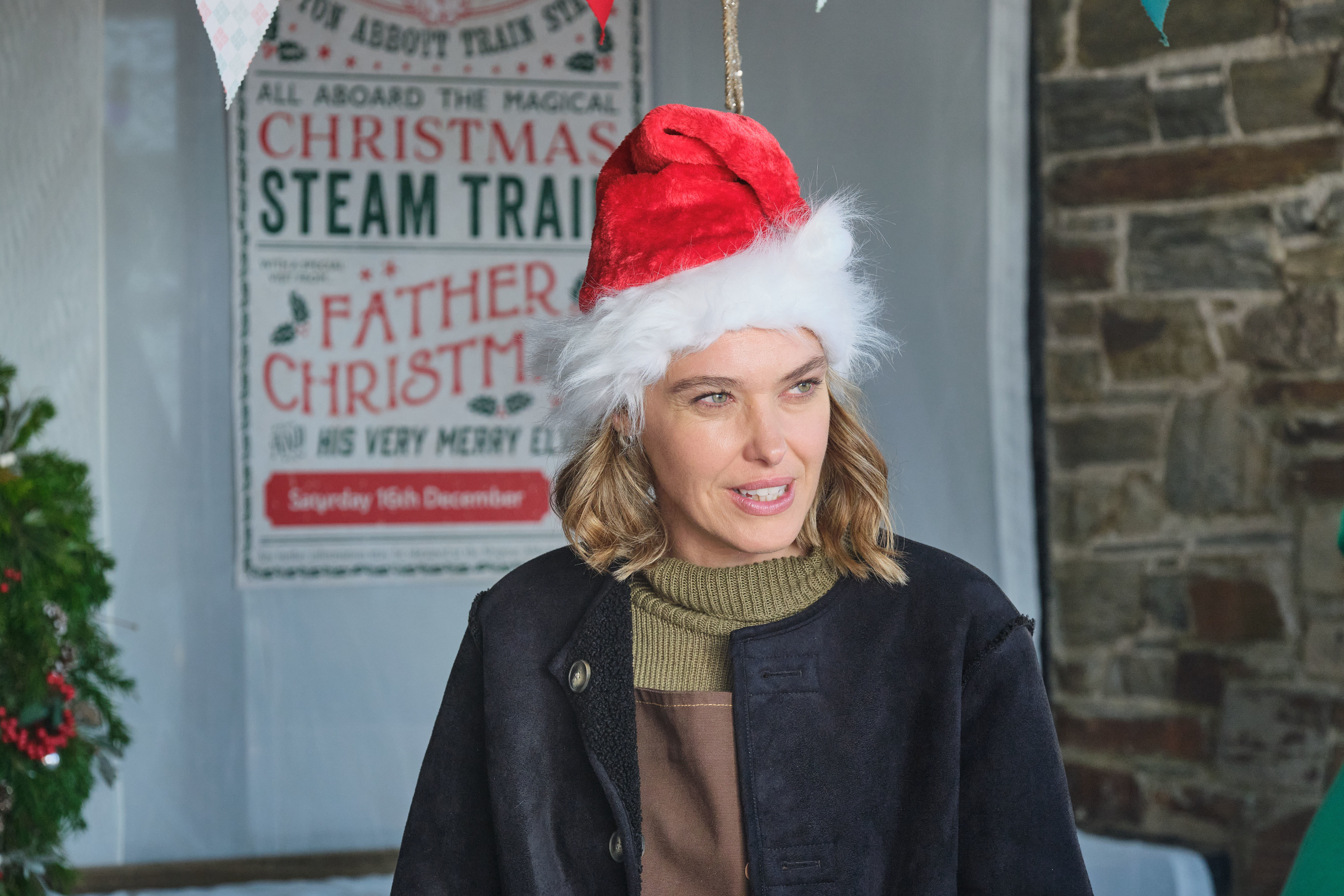 Martha (Sally Bretton) stands at the Christmas market in Shipton Abbott wearing a Santa hat