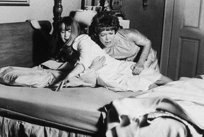 1973, American actor Ellen Burstyn restrains American actor Linda Blair on a bed in a still from the film 'The Exorcist', directed by William Friedkin. (Photo by Warner Bros./Getty Images)