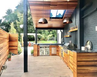 Wooden outdoor kitchen with roof and pendant lights