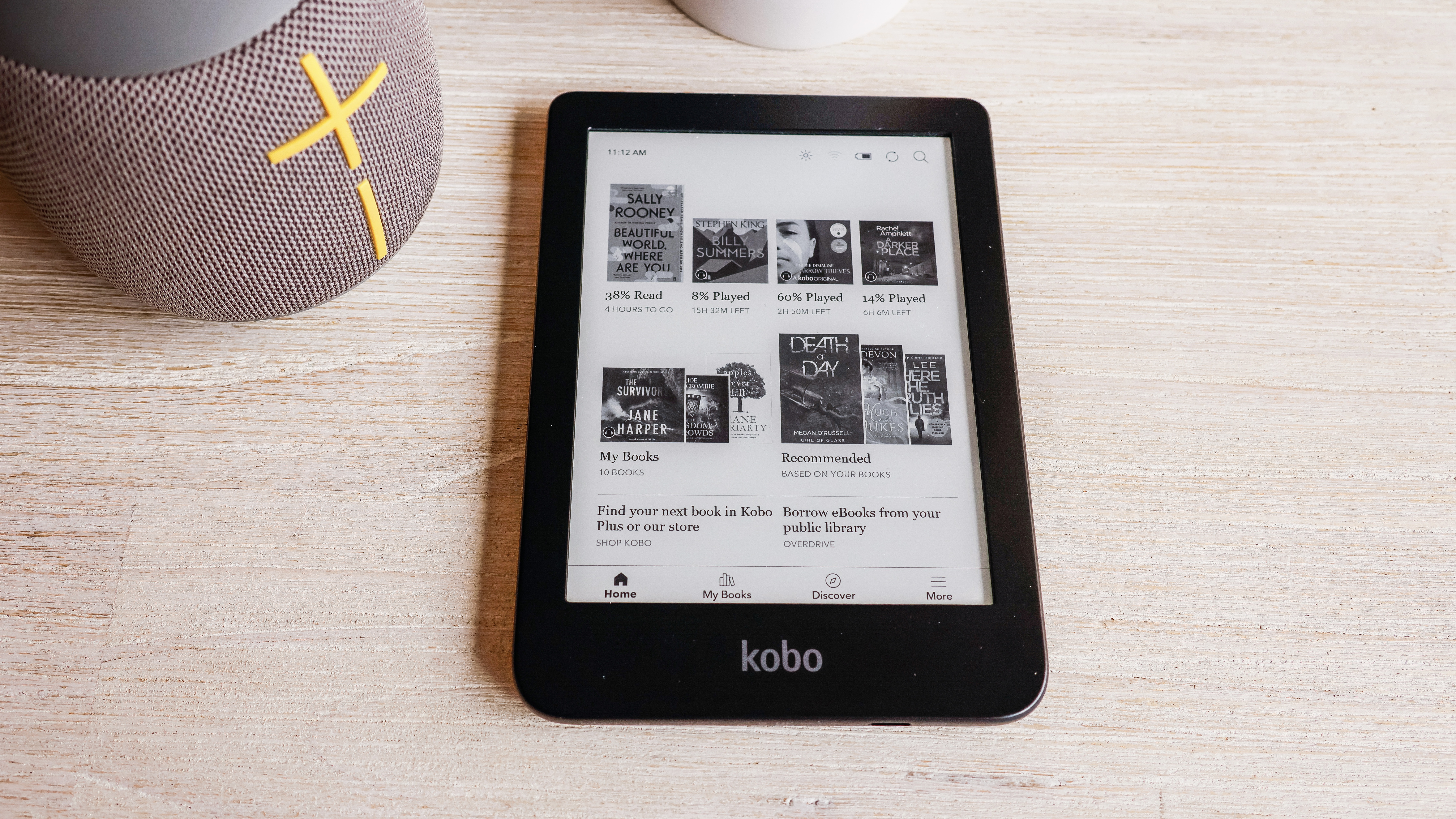 The Kobo Clara 2E laying flat on a table with the home page being displayed.