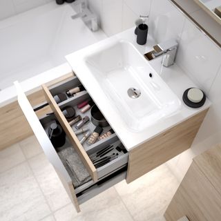 Bathroom vanity with drawer open with bath in room with neutral floor tile