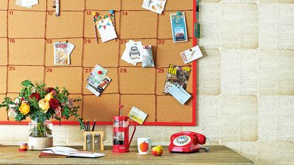 Wooden desk below large cork pinboard calender