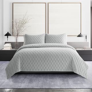 Diamond Velvet Gray Quilt Set on a bed against a white wall. 