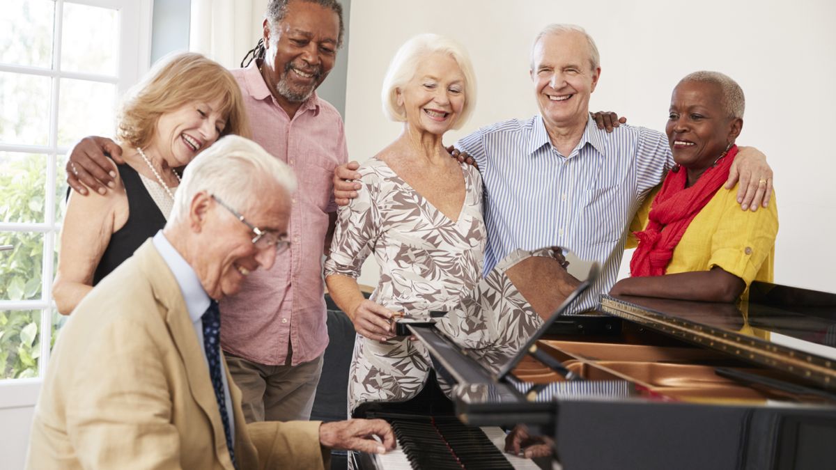 Older people singing around a piano