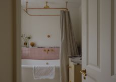 a modern vintage style bathroom showing warm neutral walls and chalky pink tiles with a freestanding bath