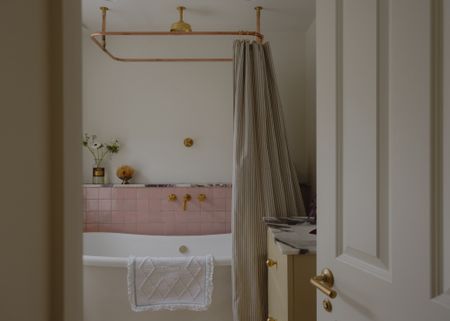 a modern vintage style bathroom showing warm neutral walls and chalky pink tiles with a freestanding bath