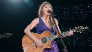 Taylor Swift playing guitar on stage at The Eras Tour