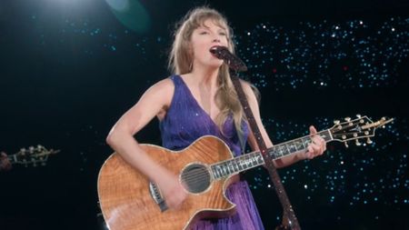 Taylor Swift playing guitar on stage at The Eras Tour