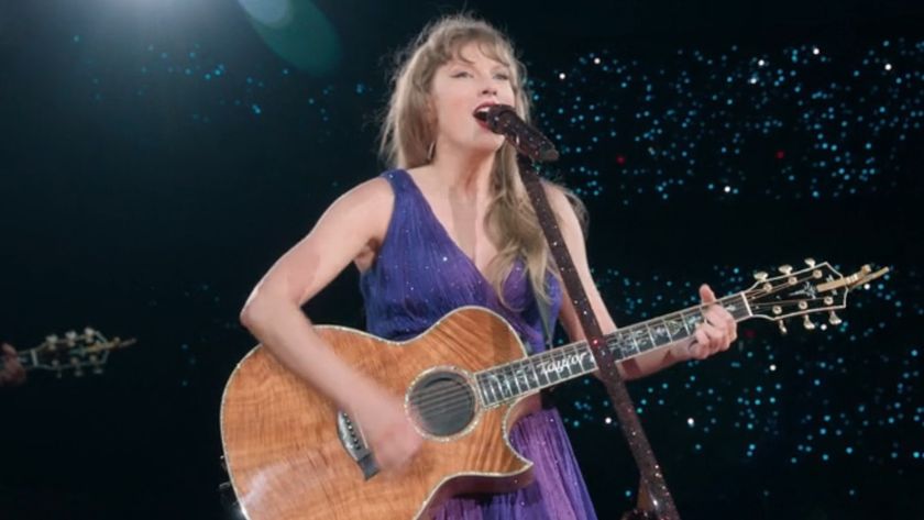 Taylor Swift playing guitar on stage at The Eras Tour