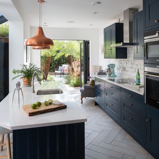 kitchen with white wall blue cabinets wooden floor and white countertop