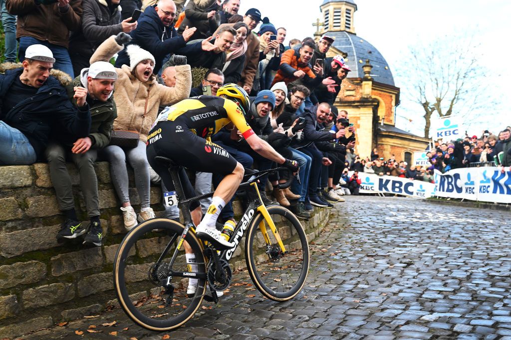 Dylan Van Baarle competes at the Muur Van Geraardsbergen while fans cheer during the 78th Omloop Het Nieuwsblad Elite 