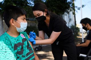 Twelve-year-old Jair Flores receives a first dose of the Pfizer Covid-19 vaccine at a mobile vaccination clinic on May 14, 2021 in Los Angeles, California. 