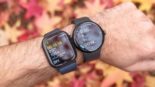 Close up of the Apple Watch 10 (left) next to the Pixel Watch 3 on a user's wrist with colorful leaves out of focus in the background