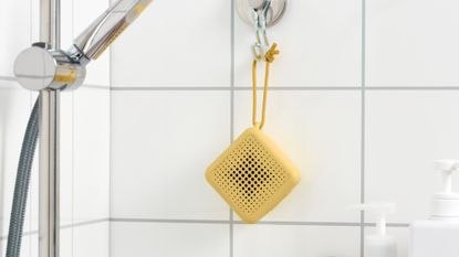 IKEA waterproof VAPPEBY speaker in yellow hanging on a hook in an all-white shower