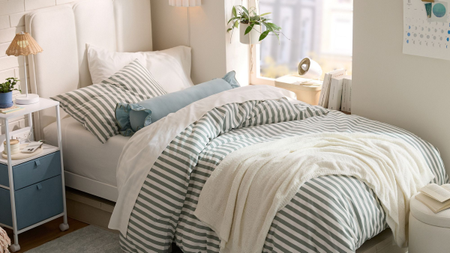 Coastal-inspired dorm room bedscape styled with navy-on-cream Twin XL striped sheets