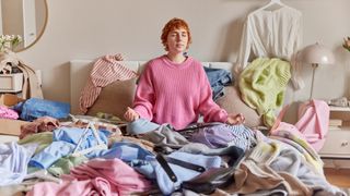 woman sitting on bed in cluttered bedroom