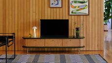 Image of a low wooden and green lacquer media console with a TV and white mushroom lamp on top.