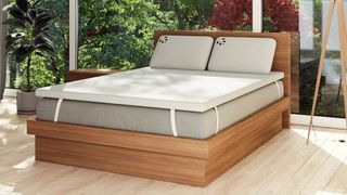 The Panda Bamboo 2" Memory Foam Mattress Topper on a grey mattress in a bright, modern bedroom overlooking a green garden.