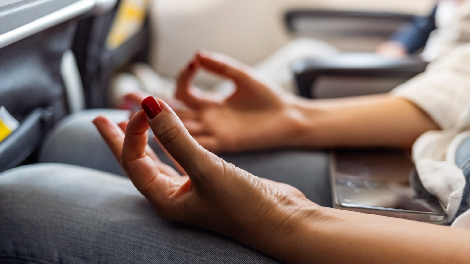 Person in airplane with aerophobia doing yoga to relax while sitting in airplane seat