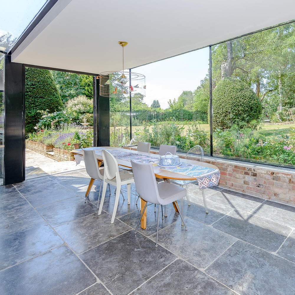 Conservatory with table and chairs on grey tiled floor with hanging decorated light
