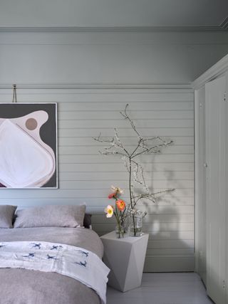 A bedroom with panelled walls painted in a soft pale sage green