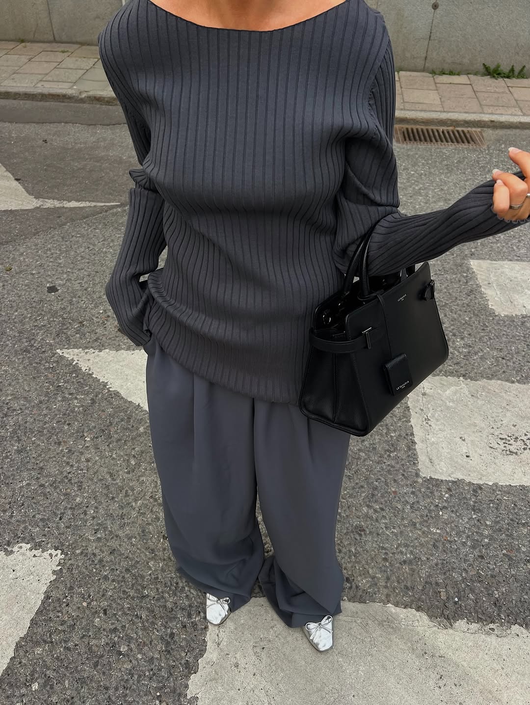 Hannah Johansson wearing a grey jumper and grey wide-leg trouser.