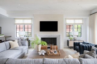 white living room with light blue sofa, fireplace, wooden coffee table and dark blue accent chairs
