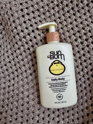 Sun Bum's Daily Body sunscreen on a glittery, textured background.