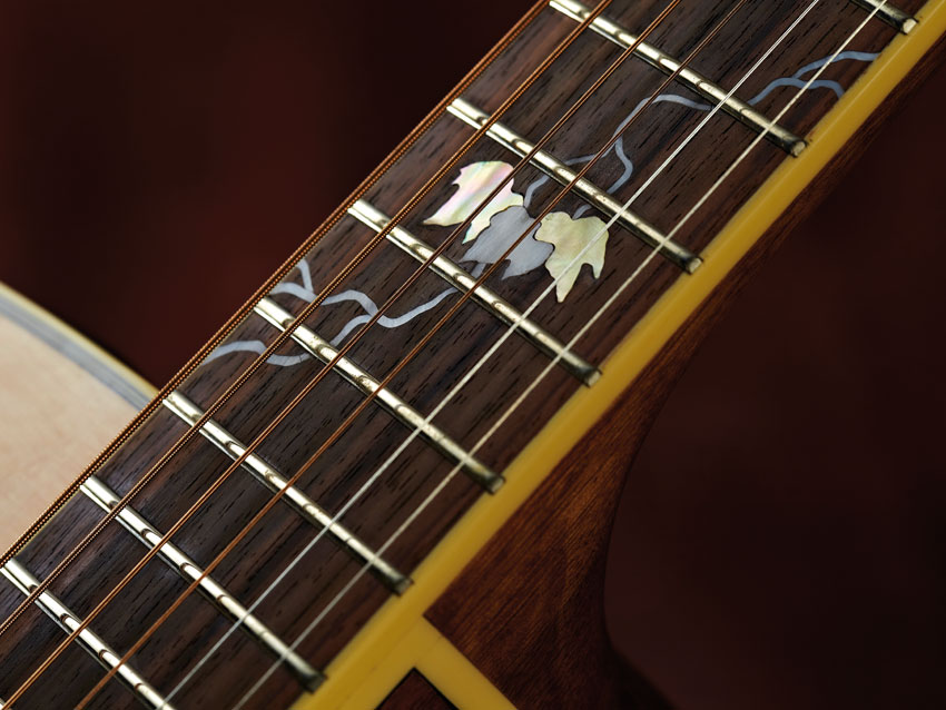 The fingerboard features a 'growing vine' motif in mother-of-pearl, while a three-leaf cluster sits at the 'board's 12th fret