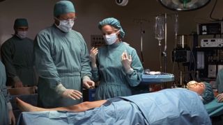 A doctor and Meryl nervously perform surgery on a patient.