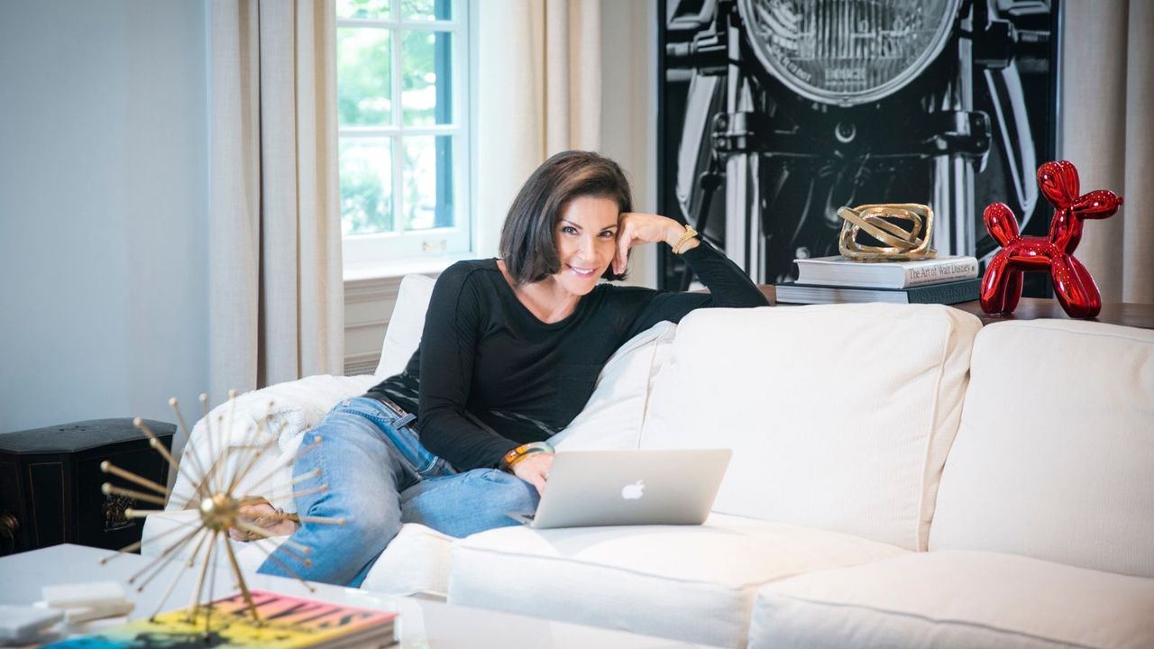 Hilary Farr seated on cream sofa