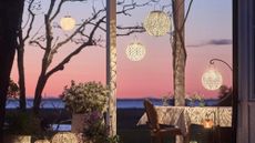 Enchanting outdoor patio at sunset featuring a dining table and several etched-metal, Art Nouveau-inspired solar lights