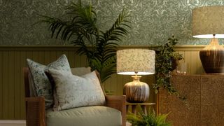 armchair with cushions next to table lamps in front of green wallpaper