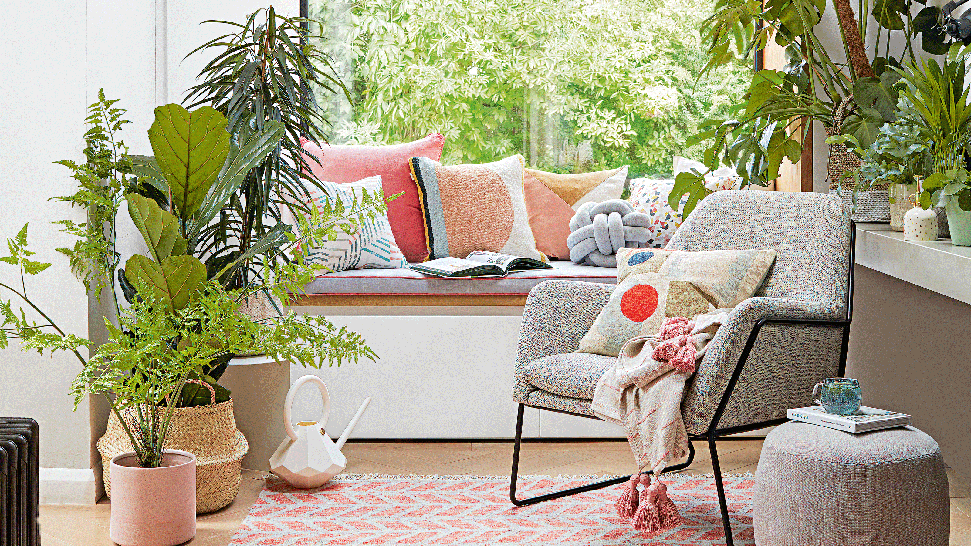 Grey armchair with window seat behind, surrounded by houseplants including a fiddle leaf fig in a belly basket