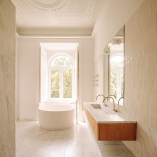 A bathroom with white marble flooring and zellige tiles on the wall